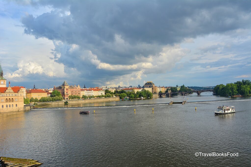 A photo of Prague from the iconic Charles Bridge with a fiery sky and the river in it