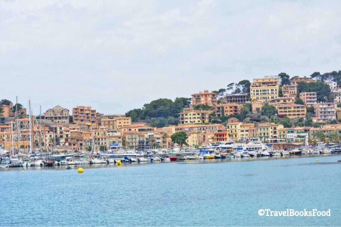 This is a photo of Port De Soller Harbour with the boats and cream houses in the distance