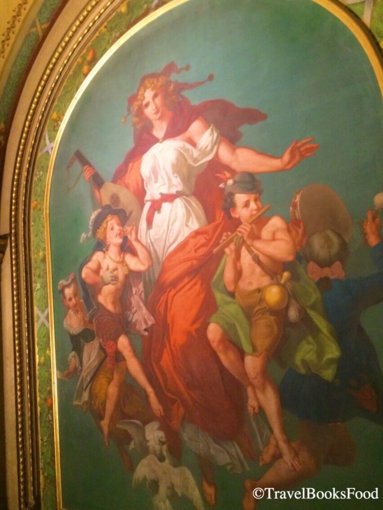 A painting of a lady surrounded by kids inside the Vienna Opera House