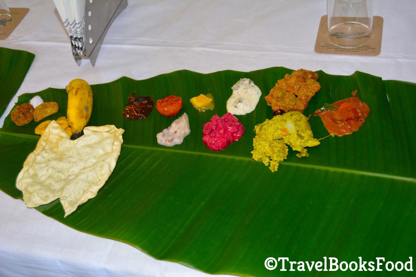 Photo of a traditional Kerala Vegetarian Meal (Sadhya) served in a green plantain leaf. There are at least 12-14 types of foods in this photo.