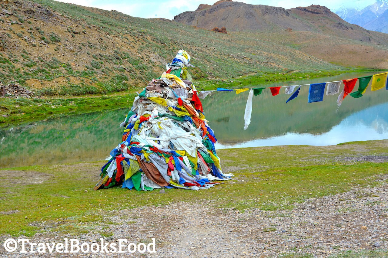 Buddhist prayer flags sitting at the edge of the blue Chandrataal lake