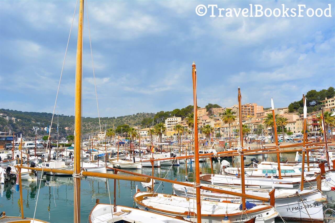 A photo of the marina of Port de soller in Mallorca, Spain. You can see lots of white boats and few cream coloured houses in the distance