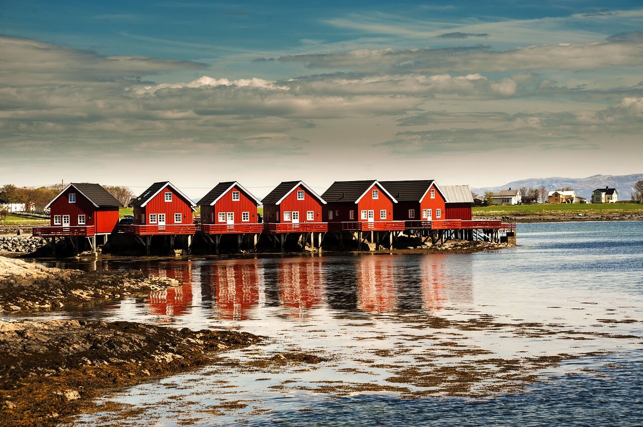 A row of red houses with a lake in front of them in Norway