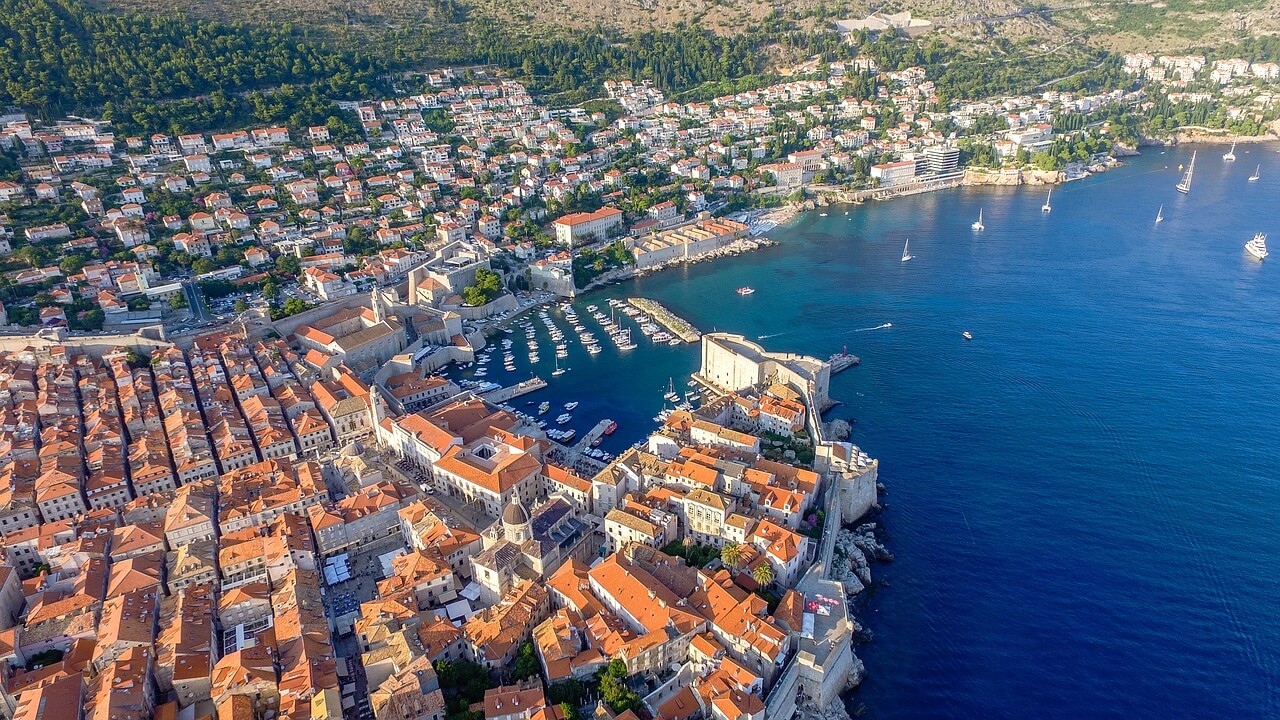 A photo of the city of Dubrovnik from above. In this photo, you can see the marina and the brown tiled buildings along the harbour