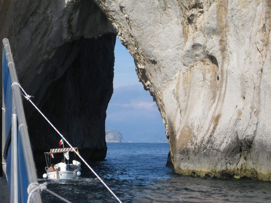 A photo of a boat doing through two cliffs or a cave