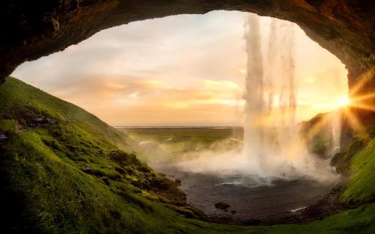 A photo of a waterfall in Iceland taken from inside a cave during sunset